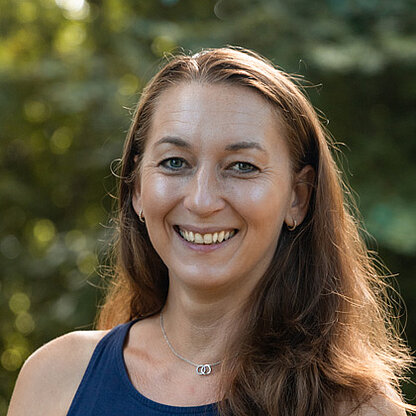 Mitarbeiterfoto vor grünem Hintergrund draußen