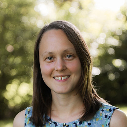 Mitarbeiterfoto vor grünem Hintergrund draußen