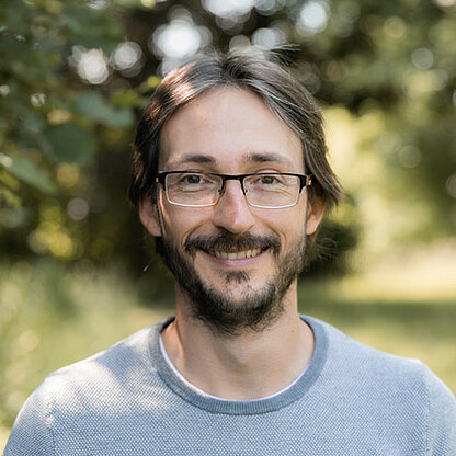 Mitrarbeiterfoto vor grünem Hintergrund draußen