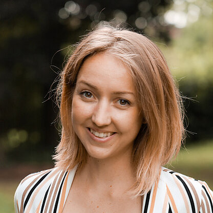 Mitarbeiterfoto vor grünem Hintergrund draußen