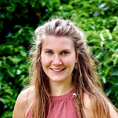 Mitarbeiterfoto vor grünem Hintergrund draußen