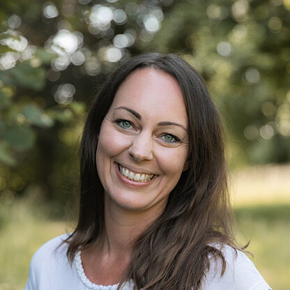 Mitarbeiterfoto vor grünem Hintergrund draußen