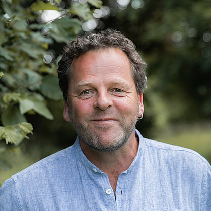 Mitarbeiterfoto vor grünem Hintergrund draußen