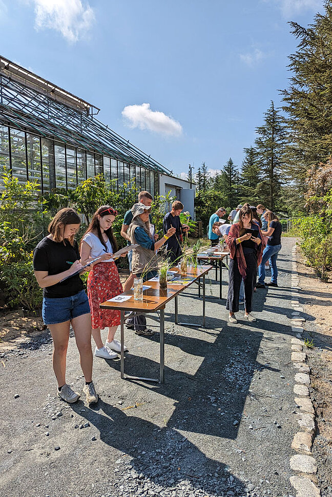BANU-Feldbotanik Prüfung im Ökologisch-Botanischen Garten Bayreuth. (Foto: Anja Gellert) Eine Gruppe Menschen steht in einer Reihe vor einem Gewächshaus.