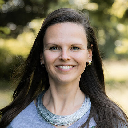 Mitarbeiterfoto vor grünem Hintergrund draußen