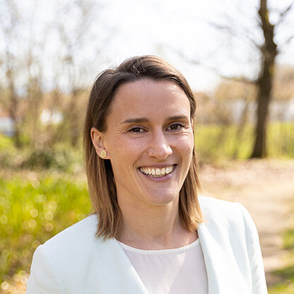 Mitarbeiterfoto vor grünem Hintergrund draußen