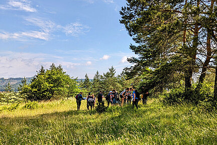 Teilnehmerinnen und Teilnehmer einer Botanik-Exkursion. (Foto: Anja Gellert) Eine Gruppe Menschen steht an einem Waldrand.