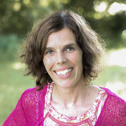 Mitarbeiterfoto vor grünem Hintergrund draußen