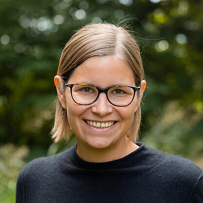 Mitarbeiterfoto vor grünem Hintergrund draußen